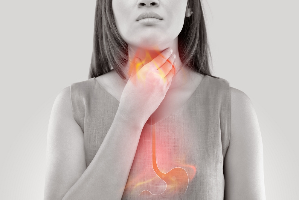 A woman holding her throat with red shading showing heartburn