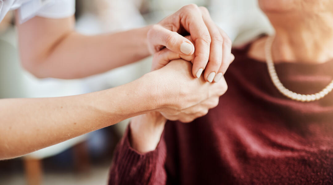 Getty Images-carer-and-older-patient-holding-hands-in-caring-way