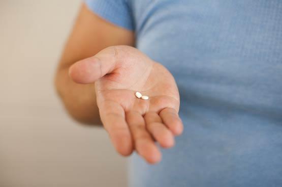 Person holding two pills in their hand